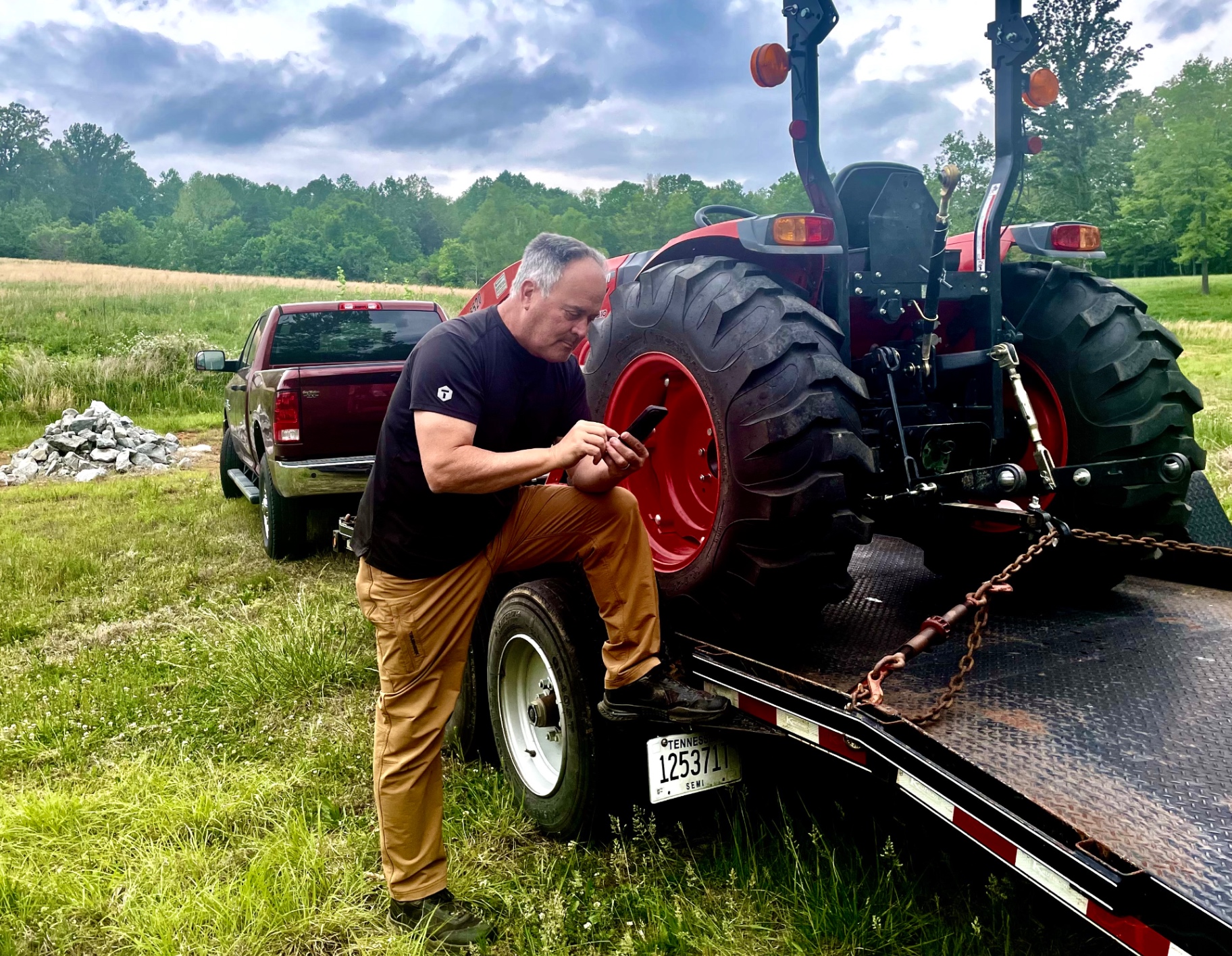 Founder using the TRUEHOUR application beside a tractor and equipment trailer.